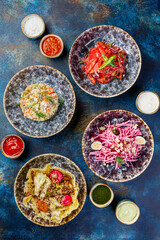 Bowls filled with different types of food including Middle Eastern salads. Table with many bowls with food on it.