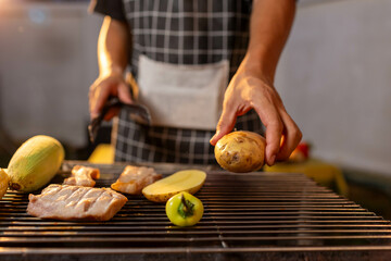 A man enjoys a summer barbecue outdoors, grilling meat and vegetables over open flames, surrounded by friends, smoke, drinks, and weekend freedom.
