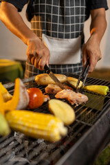 A glowing barbecue grill sizzles with assorted meats and vegetables, flames and smoke rising in the dark, capturing the essence of a summer cookout.
