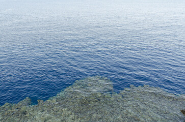 Tranquil resort features expansive ocean view with calm, rippling water. Blue hues dominate,...
