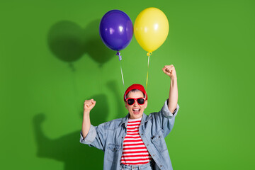 Joyful woman celebrating with balloons on a vibrant green background wearing a colorful outfit and cheerful expressions