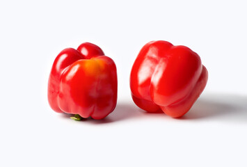 On a white background are two red peppers. The peppers are ripe and located next to each other.