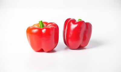 On a white background are two red peppers. The peppers are ripe and located next to each other.