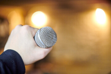 Focused view of hand gripping microphone tightly, symbolizing anticipation of performance and...