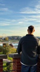 Man is admiring the landcape before the sunset in travel 
Is wearing shirt and the weather is perfect