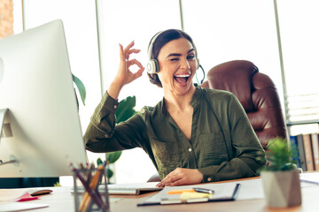 Energetic businesswoman wearing headphones, smiling confidently while working productively in a...