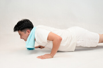 man performing push-ups in white clothes on a neutral background