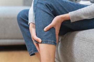 Fototapeta premium Woman get cramp on the leg sitting on sofa