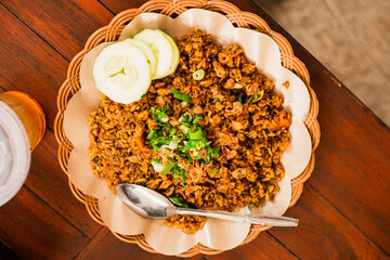 Freshly cooked fried rice on a woven bamboo plate with oil paper lining