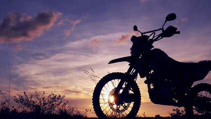 Motorcycle Silhouette Against a Sunset: A stunning silhouette of a rugged motorcycle dominates the...