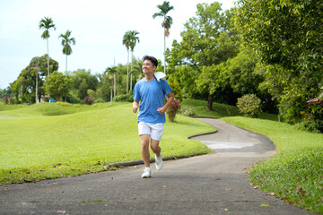 young man jogging outdoors in a park with vibrant greenery and trees around