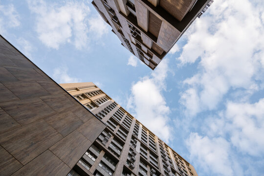 Bottom view of tall multi-story buildings against blue clody sky