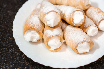 Fragrant puff pastry tubes with protein cream on a white plate. Cooking sweet pastries