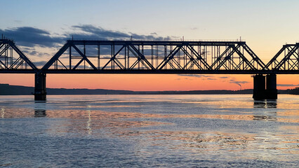 Railway bridge over the river at sunset