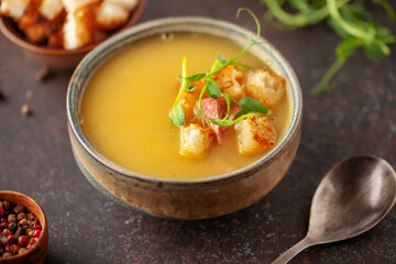 Pea soup with pieces of bacon, croutons and parsley in a bowl