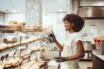 Smiling Baker Organizing Freshly Baked Goods in a Modern Bakery Kitchen