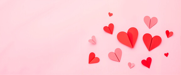 Colorful handmade paper hearts on pink backdrop, love celebration