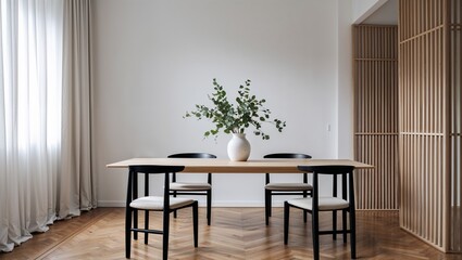 A dining room with a wooden table chairs and a vase of greenery in a minimalist styled interior space