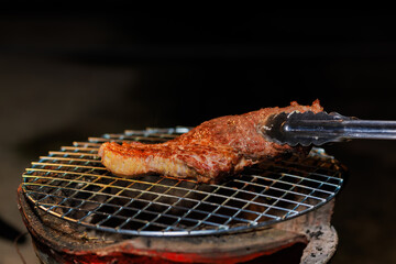 A perfectly grilled beef steak rests on a hot barbecue grill, ready to be served at a lively outdoor party or festive gathering.