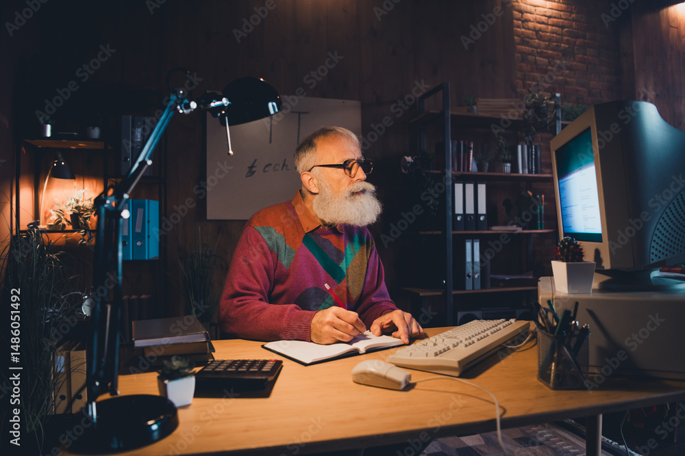 Poster elderly man working on computer in cozy home office, involved in programming and reflecting on it an