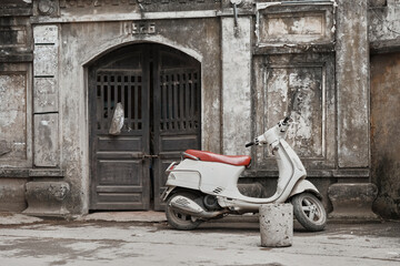 White scooter parked in front of an antique doorway in Hanoi, Vietnam's historical architecture