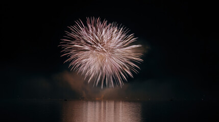 Fireworks bursting over lake with reflections in water