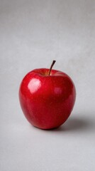 Glossy Red Apple with Natural Imperfections on Light Grey Background