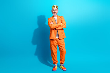 Charismatic middle aged man in bright orange suit posing against vibrant blue background exuding confidence and style