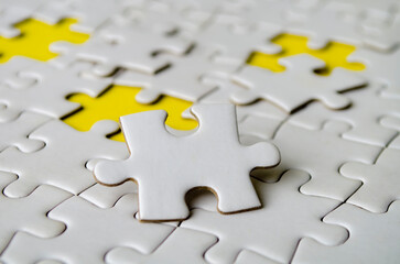 Obraz premium Side close up of white jigsaw puzzle pieces placed on a bright yellow background with customizable space on jigsaw for text or ideas.