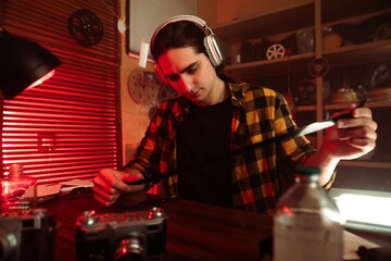 Young Man with Headphones Examining Camera in Retro Photography Studio