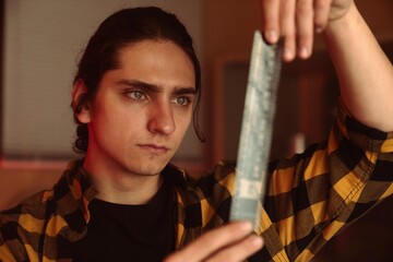 Man examining photographic film in a darkroom with intense focus