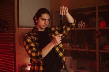 Man examining photographic film in a darkroom with intense focus