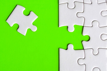 Fototapeta premium Connecting missing white jigsaw puzzle symbolizes partnership and unity on green background