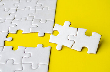 Fototapeta premium Close up view of missing white jigsaw puzzles, symbol of partnership and unity on yellow background