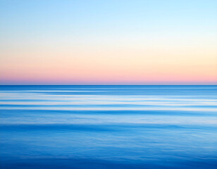 Obraz premium Calm ocean waves under a pastel-colored sky at sunset, creating a serene and tranquil seascape