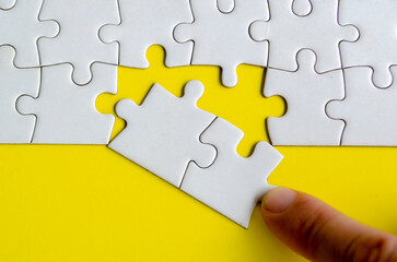 Fototapeta premium Hand placing missing jigsaw puzzles. A simple yet powerful concept of puzzle parts representing solutions unity and purposeful connection