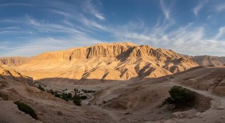 Naklejka premium Desert Mountain Range Landscape with Winding Road and Distant Village