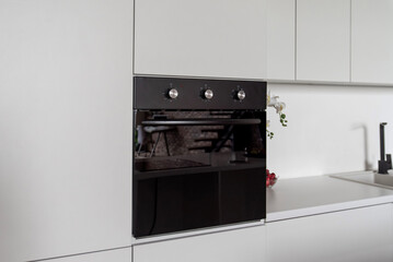 Modern black built-in oven in white kitchen interior