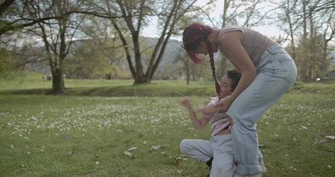 A mother and her young son enjoy a playful day at the park, filled with laughter and tickles on a sunny spring day.