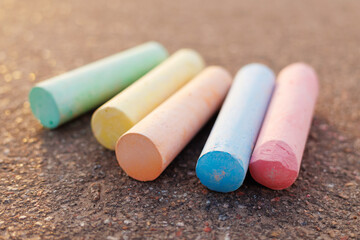 Colorful chalk pieces lie diagonally on a rough outdoor surface, ready for creative art and childhood fun.
