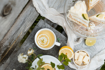 A soothing cup of tea with lemon slice and flowers on a rustic table, alongside lime slices and...