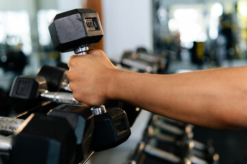 Bodybuilder picking up dumbbell in gym for fitness training