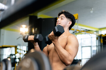 Young adult man is lifting weights in the gym