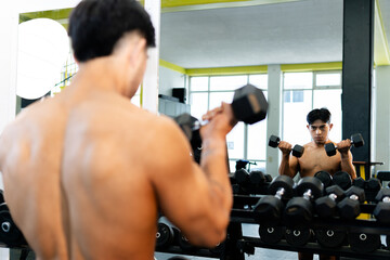 Bodybuilder lifting dumbbells and admiring himself in mirror