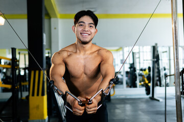 Young bodybuilder doing cable crossover exercise in gym