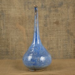 Handmade blue ceramic vase with tall neck against a rustic burlap backdrop