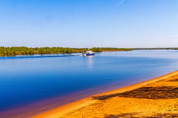 River boat on a sunny day with sandy beach and blue sky.