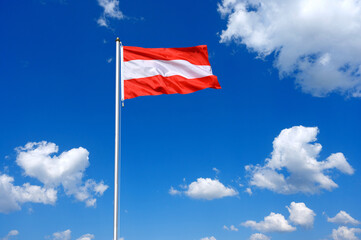 The flag of  Austria flutters in the wind in a blue sky with white clouds