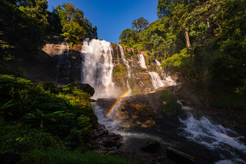 Wachirathan waterfall Chiang Mai is surrounded by lush greenery, with a vibrant rainbow forming in the mist. Water droplets hit by sunlight create rainbows that we can see all day long..