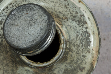 Top view of an open screw cap on an old tin bottle. The rough metal surface highlights the wear and functional charm of rugged industrial design.